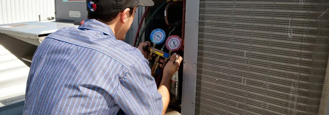 HVAC technician servicing a condenser unit in Williamstown